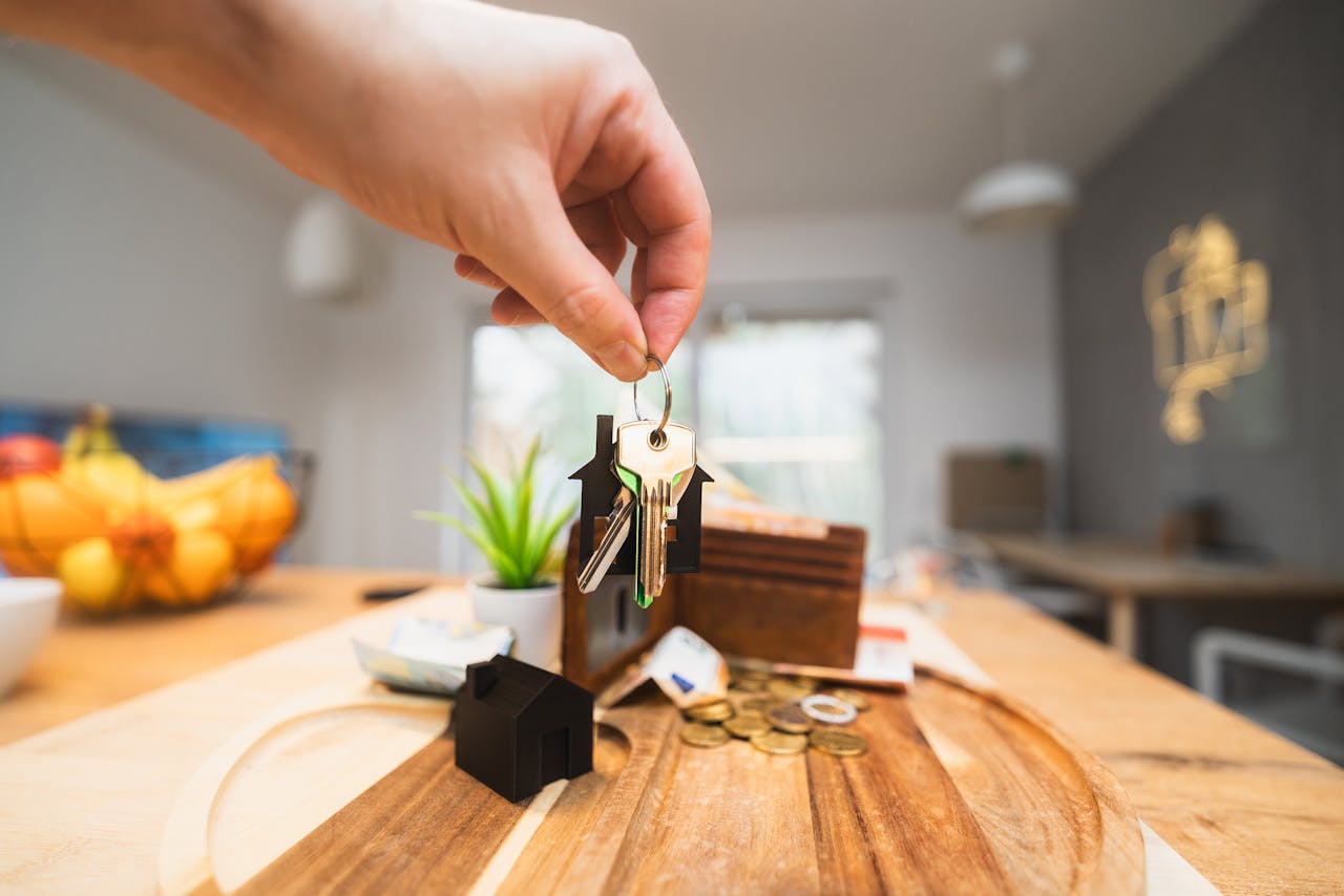 gallery-5 Hand holding keys in a modern living room setting, symbolizing home ownership or real estate investment.