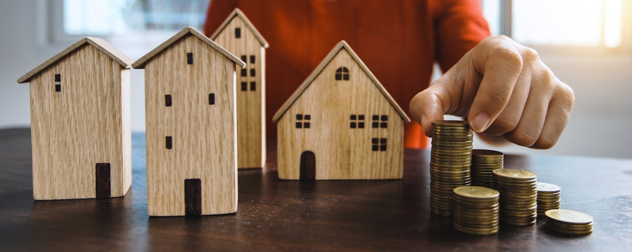 services-01 Planning investments with stacked coins and model houses on a table.